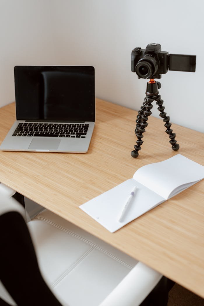 From above of comfortable office chair at table with laptop camera on tripod and opened notepad